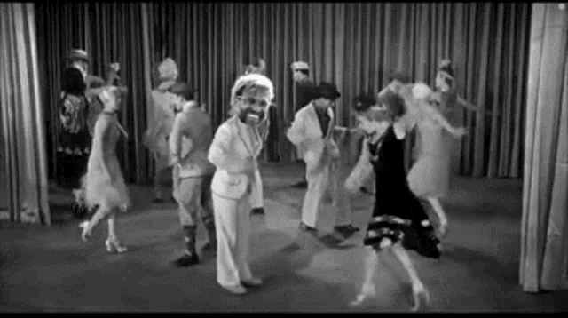 a group of people are dancing in a room with a curtain behind them .