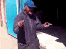 a man wearing a blue hat is smoking a cigarette while holding a camera .
