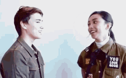 a man and a woman are standing next to each other and laughing .