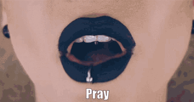 a close up of a woman 's mouth with black lipstick and the word pray above it