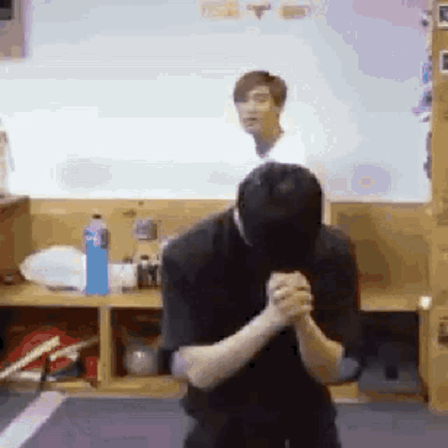 a man is standing in a room with his hands folded in front of him .