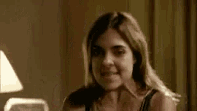 a woman in a black bra is sitting on a bed smiling .