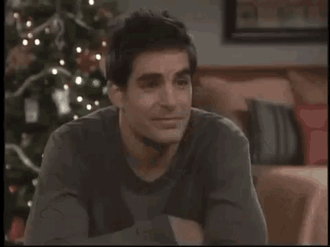 a man is sitting on a couch in front of a christmas tree in a living room .