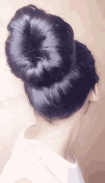 a woman has her hair in a bun and has a white shirt on