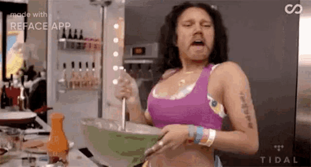 a woman in a pink tank top is cooking in a kitchen with a spoon in a bowl .