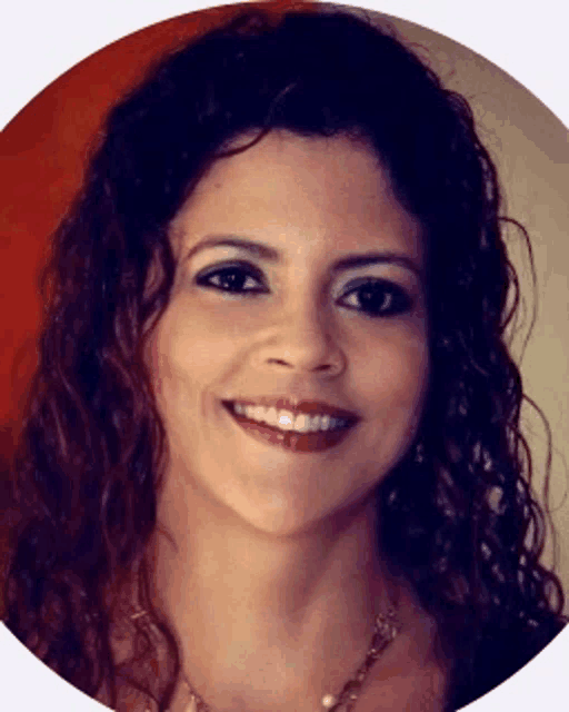 a woman with curly hair and a necklace smiles for the camera