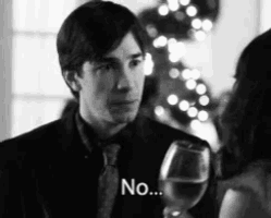 a man in a suit and tie is holding a glass of wine and talking to a woman .