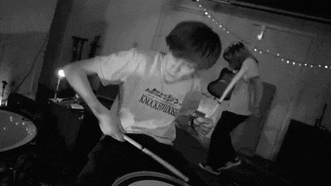 a man wearing a shirt that says knocked down is playing drums