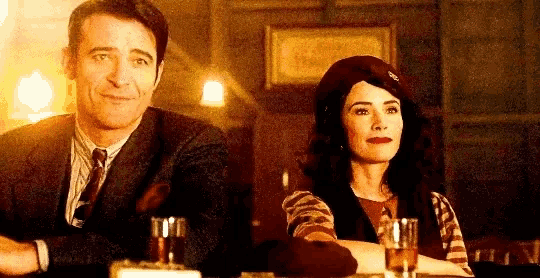 a man and a woman are sitting at a table with glasses of alcohol .