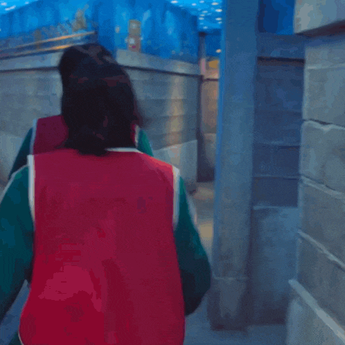 a man in a green and red jacket is carrying a woman