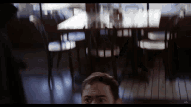 a blurry picture of a man in a restaurant with a blurred image of tables and chairs behind him
