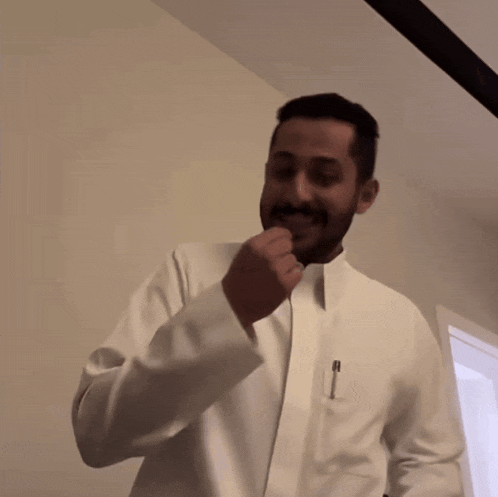 a man with a beard wearing a white jacket has a pen in his pocket