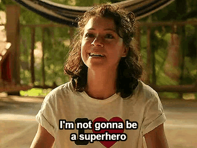a woman wearing a white t-shirt that says i 'm not gonna be a superhero