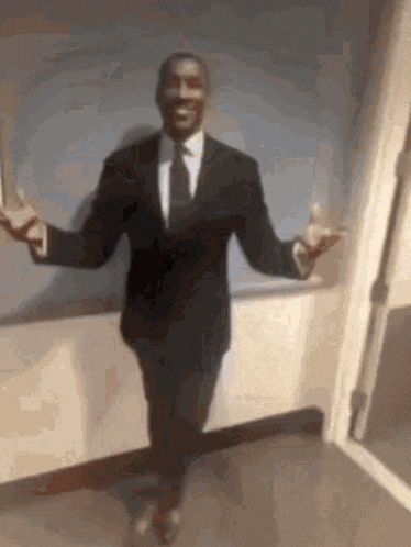 a man in a suit and tie is dancing with his arms outstretched .