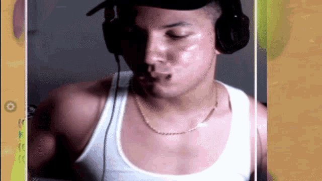 a man wearing headphones and a tank top looks at the camera