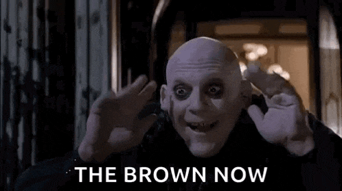 a bald man is waving his hands in front of a door with the words `` the brown now '' .