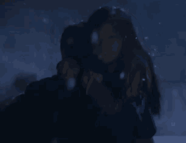 a man and a woman are hugging each other in the snow .