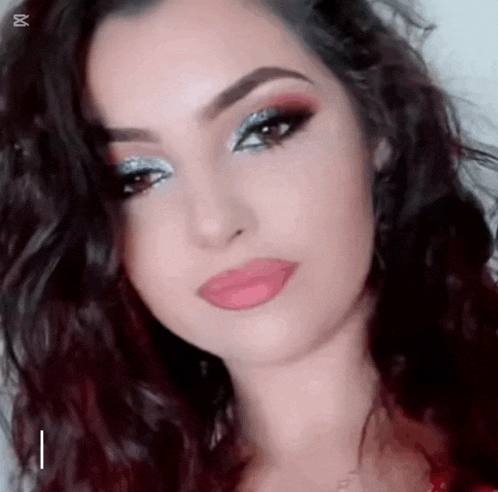 a close up of a woman 's face with makeup on and a necklace .