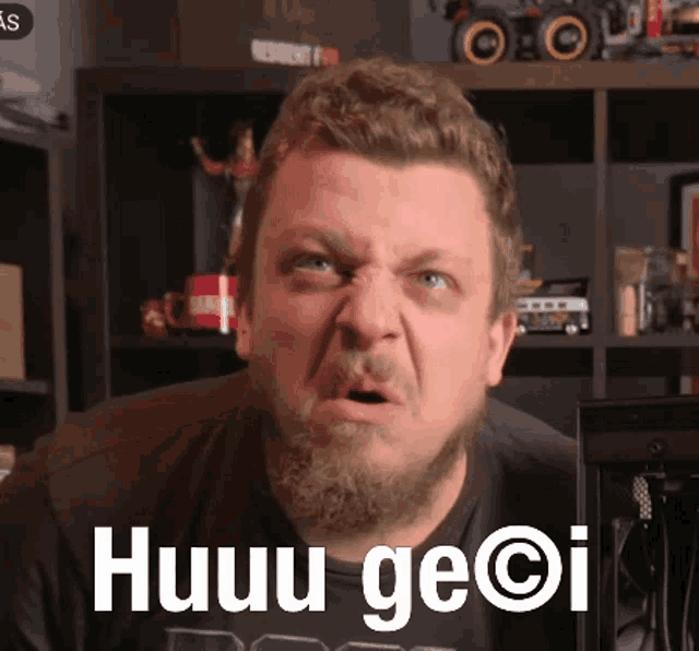 a man with a beard is wearing a black shirt that says huuu ge @ i on it