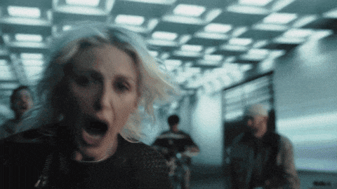 a woman is screaming in a dark hallway with a man in the background