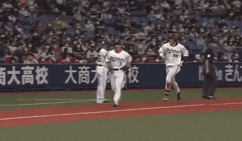 a couple of baseball players running on a field with chinese writing on the wall