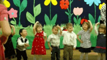a group of children are dancing in front of a floral background