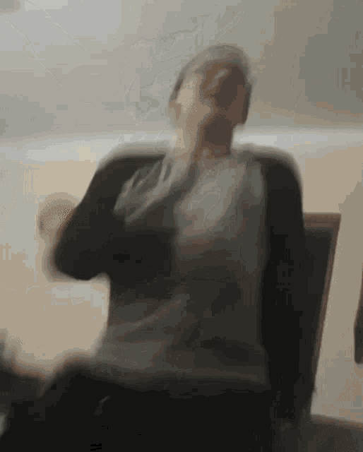a blurry picture of a man sitting in a chair with his arms outstretched .