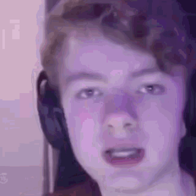 a close up of a young man wearing headphones making a funny face .