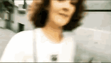 a blurry picture of a woman with curly hair wearing a white shirt .