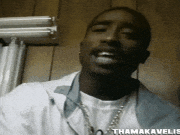 a close up of a man wearing a white shirt and a chain with the name thamakavelis written on the bottom