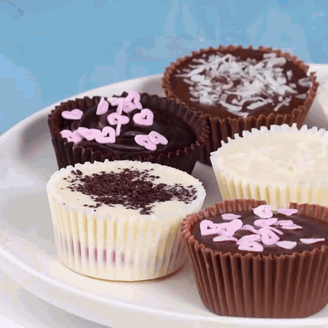 a white plate topped with a variety of chocolate cupcakes with hearts on them
