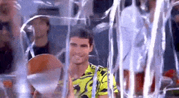 a man in a yellow shirt is standing in a clear container surrounded by streamers .