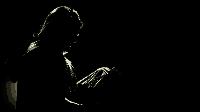 a silhouette of a man in a suit and tie in the dark