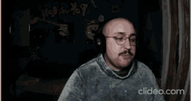 a man with a mustache and glasses is dancing in front of a wall with graffiti on it .