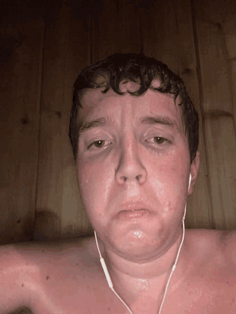 a shirtless man wearing ear buds looks tired and sweaty