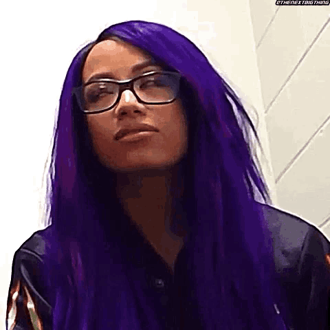 a woman with purple hair and glasses is wearing a black jacket .