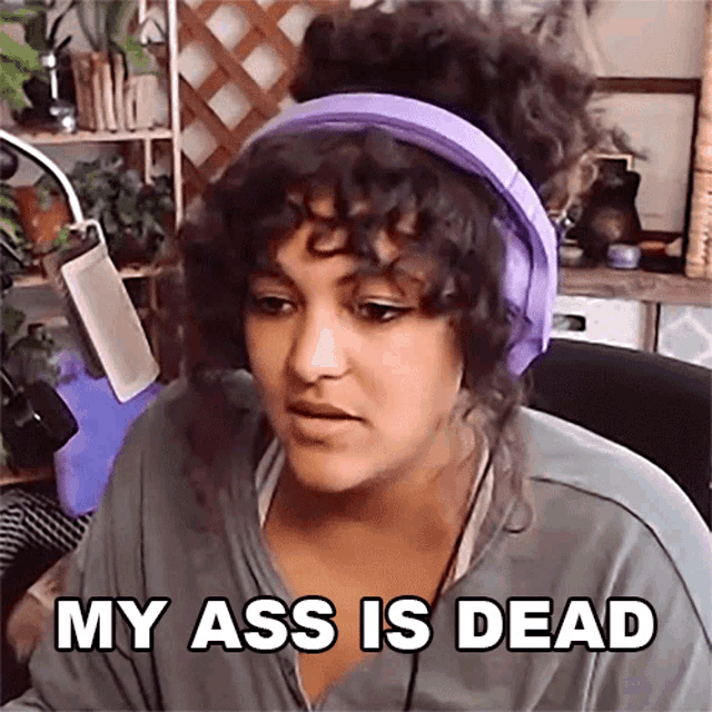 a woman with curly hair wearing headphones says my ass is dead