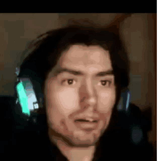 a man wearing headphones is making a funny face in a dark room .