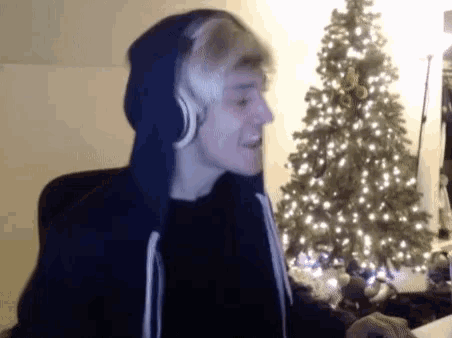 a man wearing headphones is sitting in front of a christmas tree