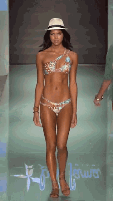 a woman in a bikini walks down the runway