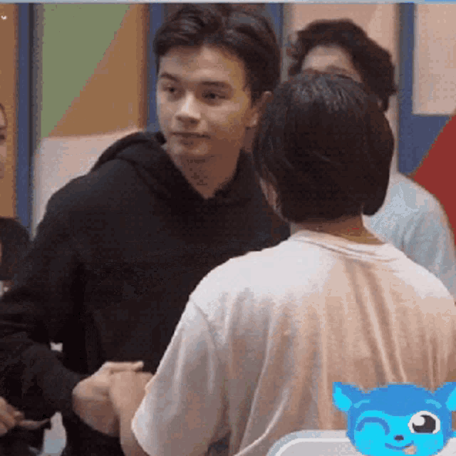 a man in a black hoodie shakes hands with another man