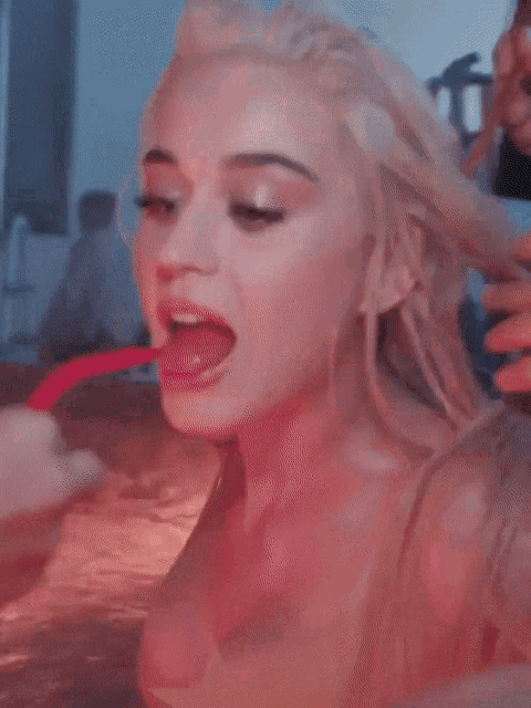 a close up of a woman in a bathtub with a red straw in her mouth