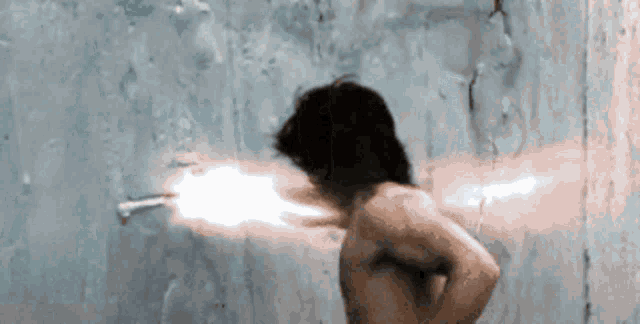 a man without a shirt is shooting a gun