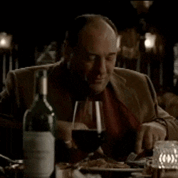 a man is sitting at a table with a bottle of wine and a glass of wine