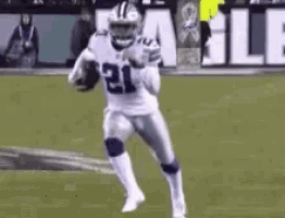 a football player in a white uniform is running with a ball on a field .