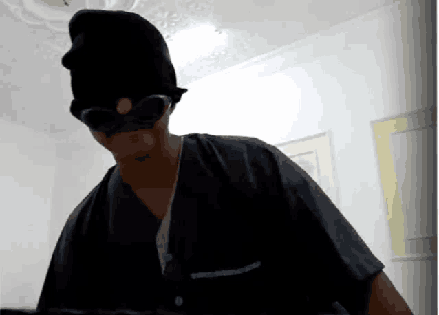 a man wearing a black mask and goggles is standing in a room