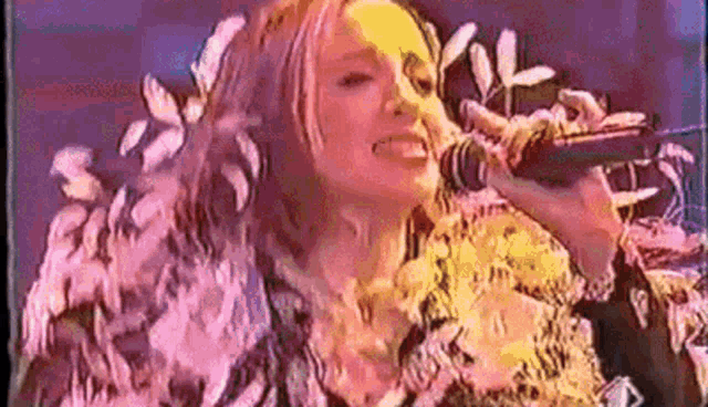 a woman is singing into a microphone while wearing a feathered coat .