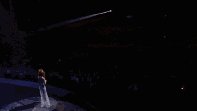 a woman singing into a microphone in front of a crowd of people