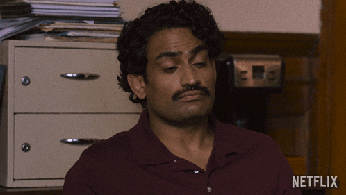 a man in a maroon shirt is sitting in front of a netflix logo