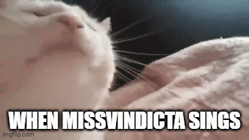 a cat is laying on a blanket with the words `` when missvindicta sings '' written above it .